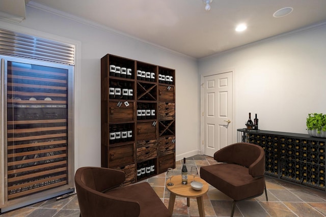 wine area with beverage cooler, stone finish flooring, and crown molding