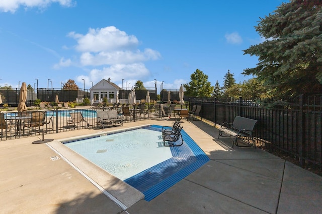 pool with a patio area and fence