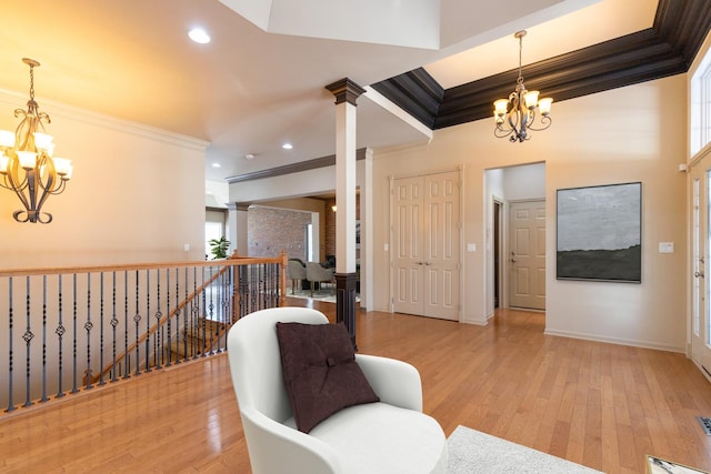 sitting room with a chandelier, light wood-style flooring, and crown molding