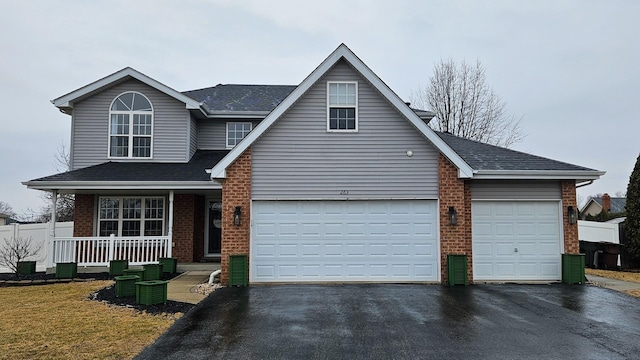 view of front facade with aphalt driveway, covered porch, brick siding, and a garage