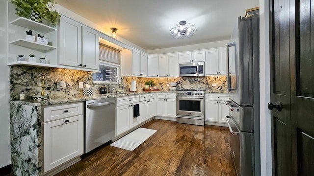 kitchen featuring white cabinets, dark wood-type flooring, light stone countertops, stainless steel appliances, and a sink