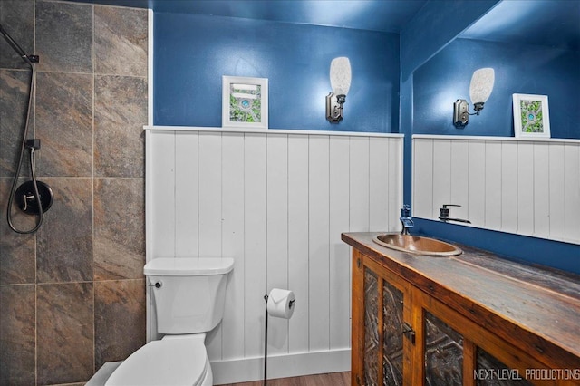 bathroom with vanity, toilet, and a tile shower