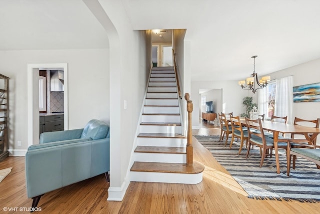 staircase featuring hardwood / wood-style flooring and an inviting chandelier