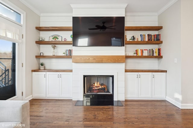 unfurnished living room featuring crown molding, dark hardwood / wood-style floors, ceiling fan, and a fireplace