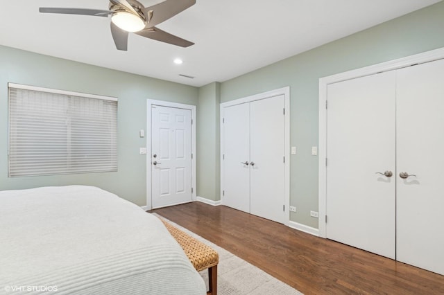 bedroom with multiple closets, ceiling fan, and dark wood-type flooring