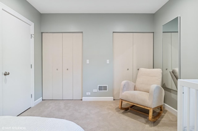 bedroom with multiple closets and light colored carpet