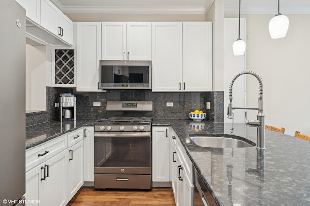 kitchen featuring appliances with stainless steel finishes, sink, dark stone counters, and white cabinets