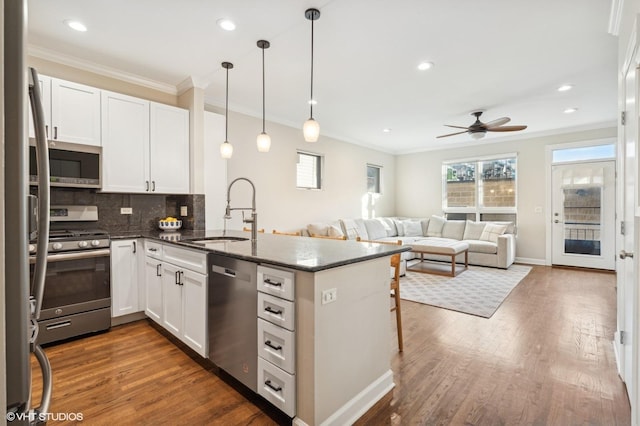 kitchen with white cabinetry, sink, stainless steel appliances, and kitchen peninsula