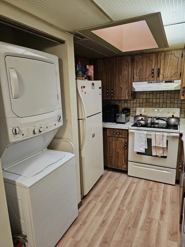 kitchen with white appliances, stacked washer / drying machine, light hardwood / wood-style floors, and backsplash