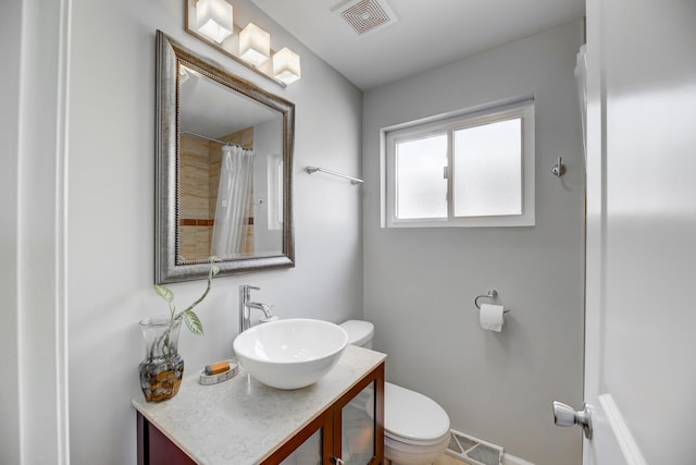 bathroom with toilet, vanity, and visible vents