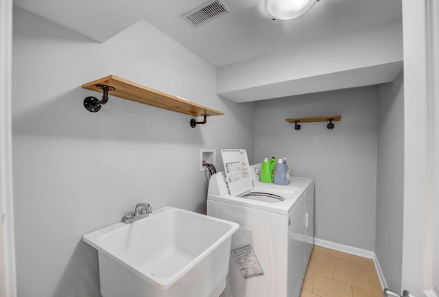 clothes washing area with laundry area, a sink, visible vents, baseboards, and washer and dryer