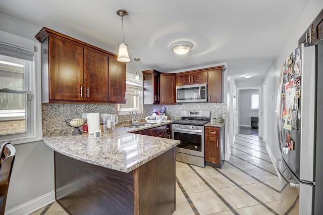 kitchen with stainless steel appliances, a peninsula, a sink, baseboards, and tasteful backsplash