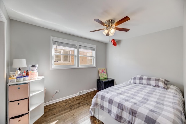 bedroom with baseboards, visible vents, ceiling fan, and wood finished floors