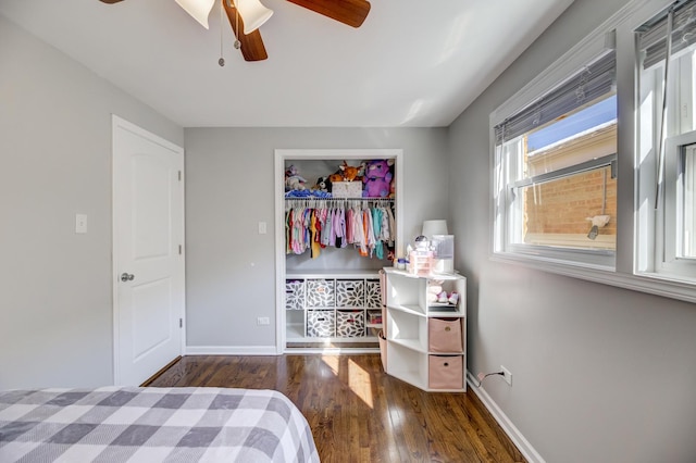 bedroom with ceiling fan, wood finished floors, baseboards, a closet, and a walk in closet