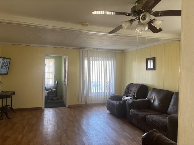 living room with ceiling fan, dark wood-type flooring, and beamed ceiling