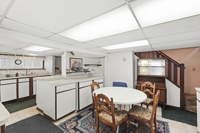 tiled dining space with sink and a drop ceiling