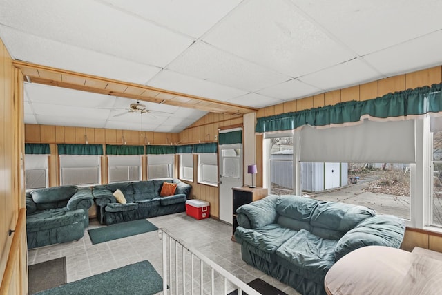 living room featuring ceiling fan, wooden walls, a healthy amount of sunlight, and a paneled ceiling