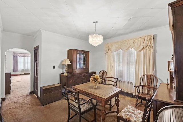 dining area with crown molding, light colored carpet, and a chandelier