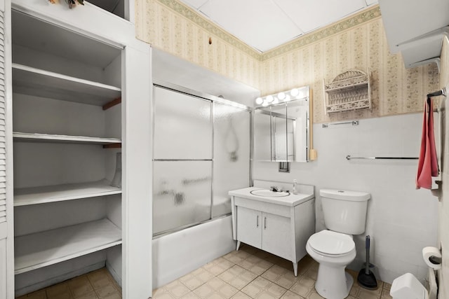 full bathroom featuring vanity, combined bath / shower with glass door, tile walls, and toilet