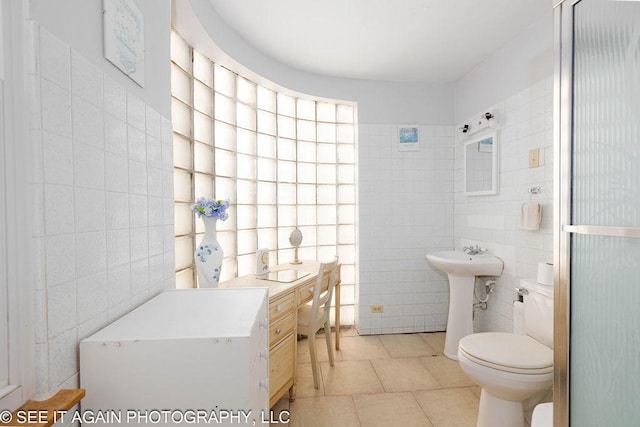 bathroom featuring sink, tile walls, and toilet