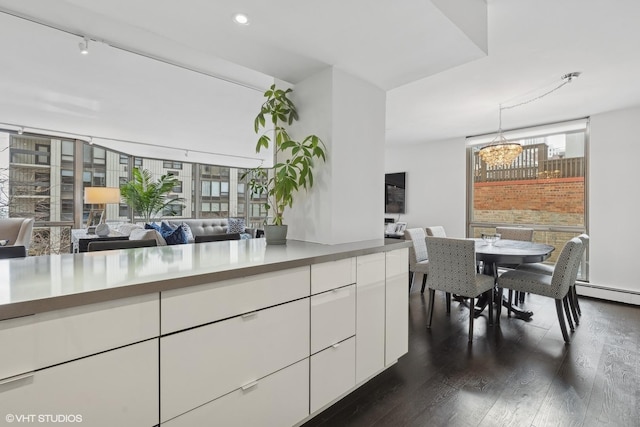 kitchen with an inviting chandelier, white cabinets, modern cabinets, dark wood finished floors, and pendant lighting