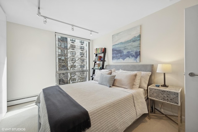 bedroom with carpet floors, rail lighting, and a baseboard heating unit