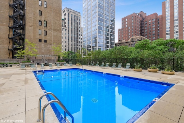 pool with a city view, fence, and a patio