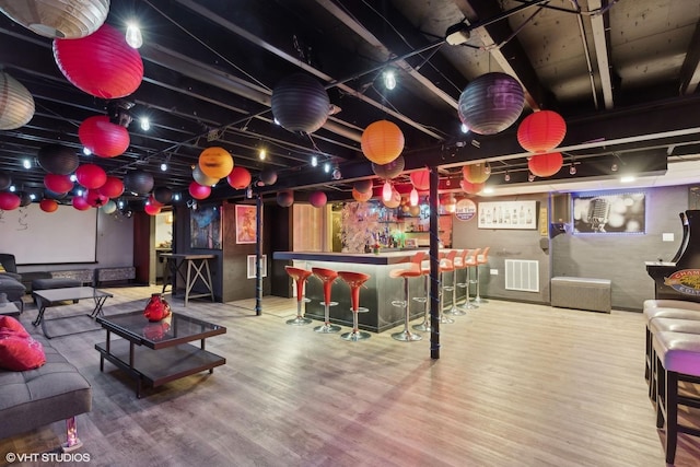 game room with visible vents, a bar, and wood finished floors