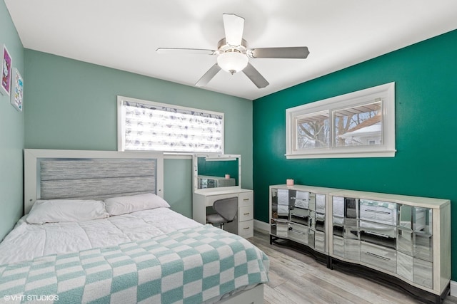 bedroom featuring light wood finished floors, ceiling fan, and multiple windows