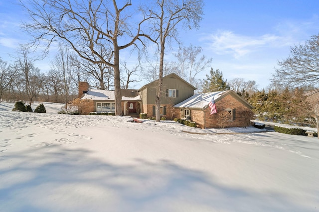 view of front of home featuring a chimney and brick siding