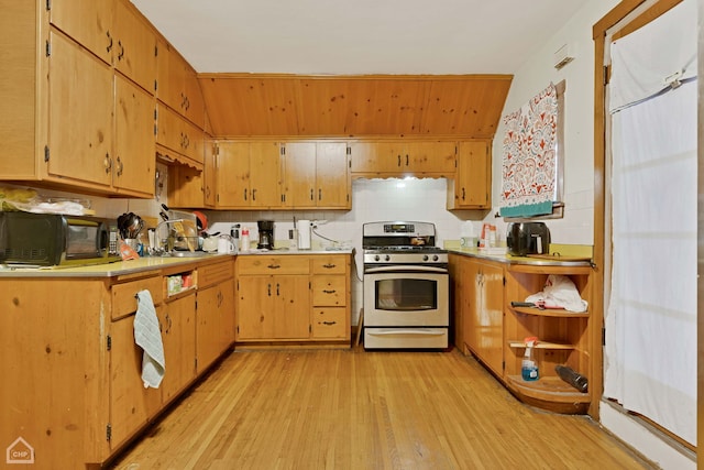 kitchen with gas stove, sink, backsplash, and light wood-type flooring