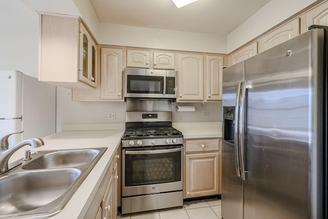 kitchen featuring light tile patterned flooring, appliances with stainless steel finishes, light brown cabinetry, and sink