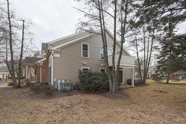 view of property exterior with central AC unit, a lawn, and a balcony