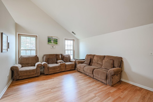 living room featuring high vaulted ceiling and light wood-type flooring