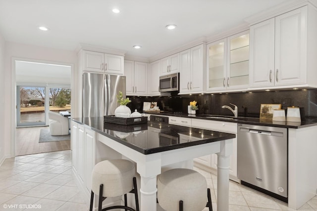 kitchen featuring white cabinetry, a center island, light tile patterned floors, a kitchen breakfast bar, and stainless steel appliances