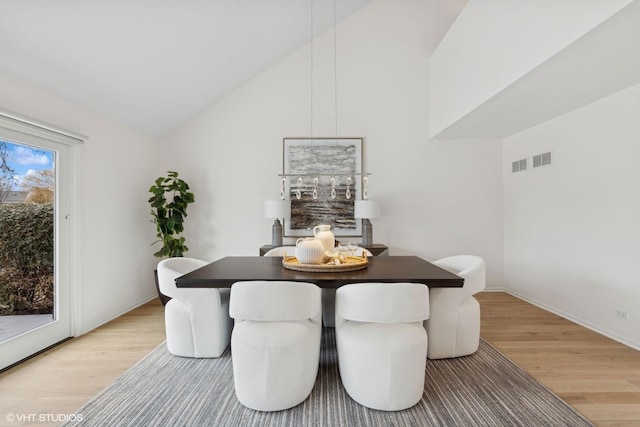 dining space featuring hardwood / wood-style floors and high vaulted ceiling