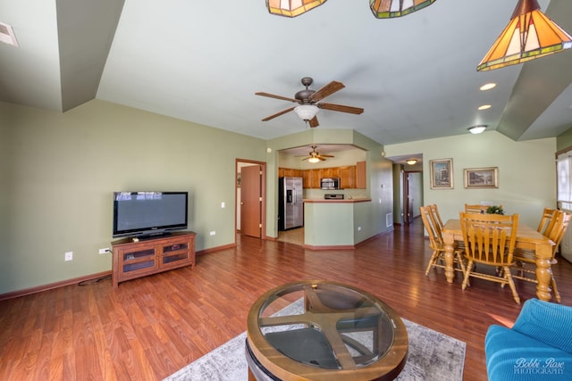 living room featuring ceiling fan, vaulted ceiling, baseboards, and wood finished floors