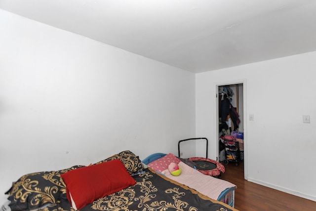 bedroom featuring a walk in closet and dark hardwood / wood-style flooring