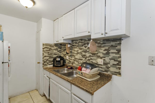 kitchen featuring light tile patterned flooring, white cabinetry, sink, decorative backsplash, and white fridge