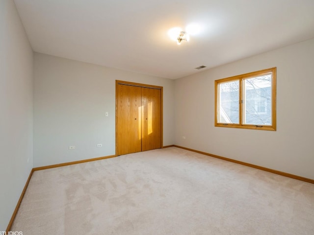 unfurnished bedroom featuring baseboards, visible vents, and light colored carpet