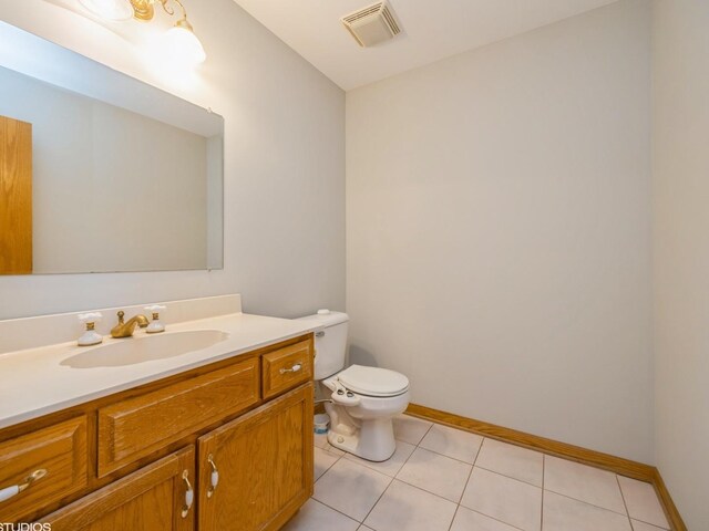 half bathroom with visible vents, toilet, vanity, tile patterned flooring, and baseboards