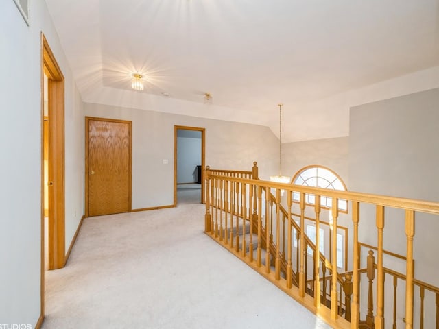 corridor with lofted ceiling, a notable chandelier, carpet floors, an upstairs landing, and baseboards