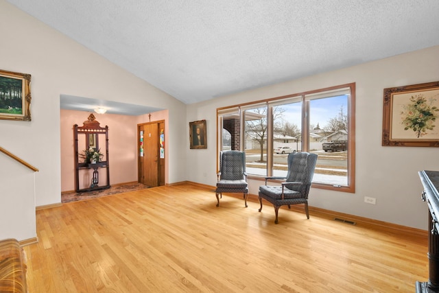 sitting room featuring vaulted ceiling, a textured ceiling, and light hardwood / wood-style floors