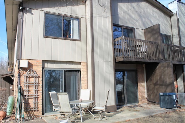 back of house featuring a patio, brick siding, a chimney, and central air condition unit