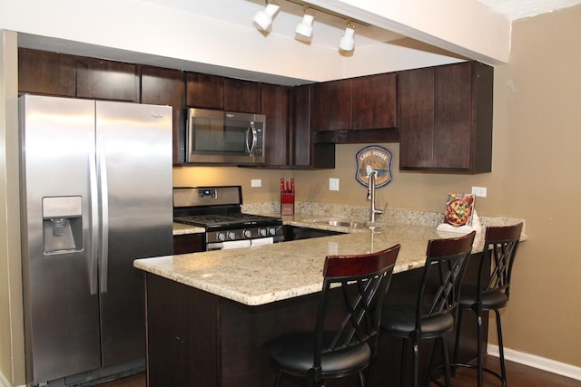 kitchen featuring sink, a breakfast bar area, dark brown cabinets, stainless steel appliances, and kitchen peninsula