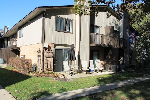 view of side of home with a lawn, a balcony, and central air condition unit