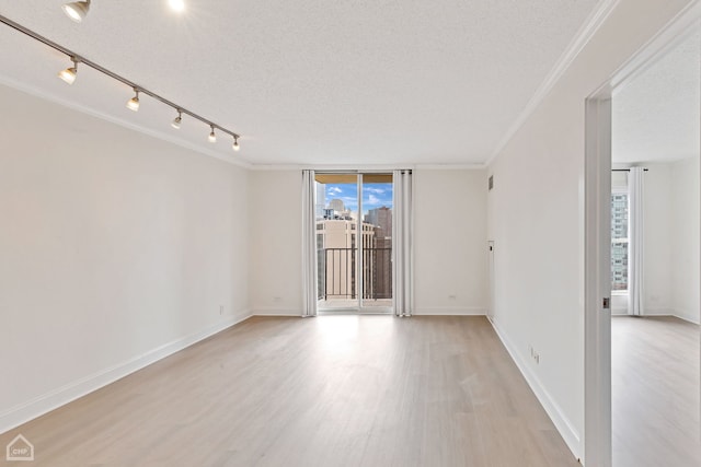 empty room featuring crown molding, track lighting, a textured ceiling, and light hardwood / wood-style floors