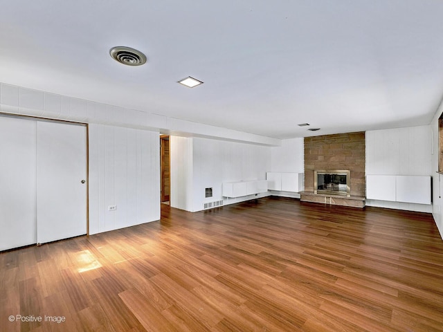 unfurnished living room featuring visible vents, wood finished floors, and a fireplace