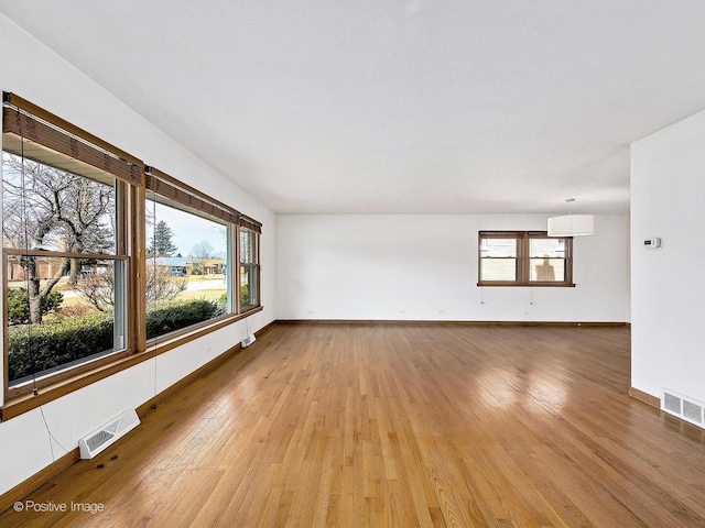 empty room featuring baseboards, visible vents, and light wood-type flooring