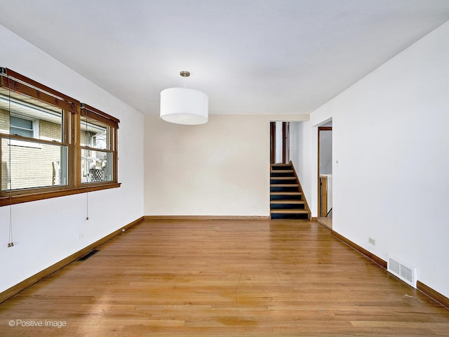 spare room with visible vents, baseboards, light wood-style floors, and stairway